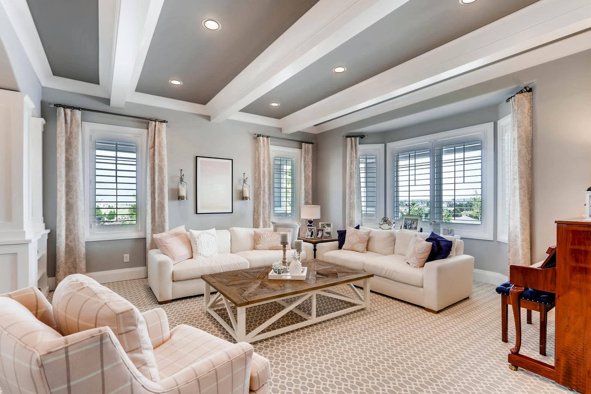 Living room with sofa sets, a central table, and carpet flooring in a large custom home by Sheffield Homes in Parker, CO
