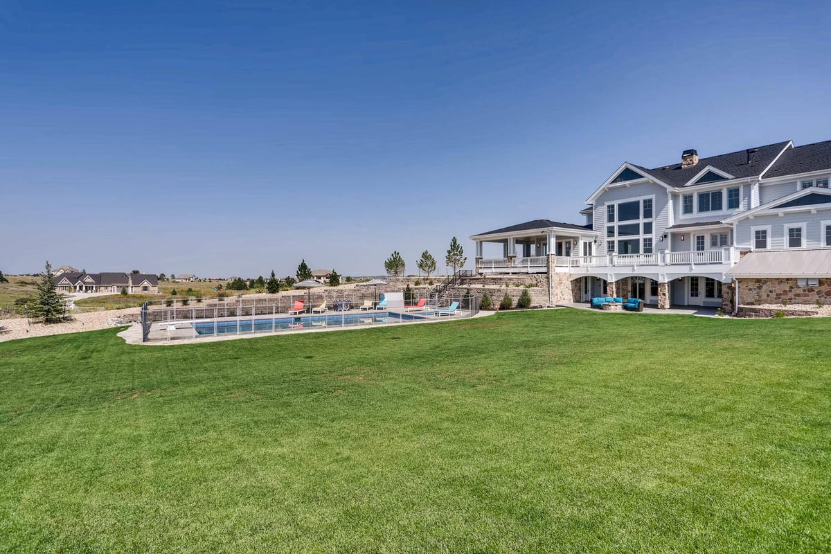 Long shot of the backyard of a large custom house with an expansive fresh grass lawn built by Sheffield Homes in Parker, CO