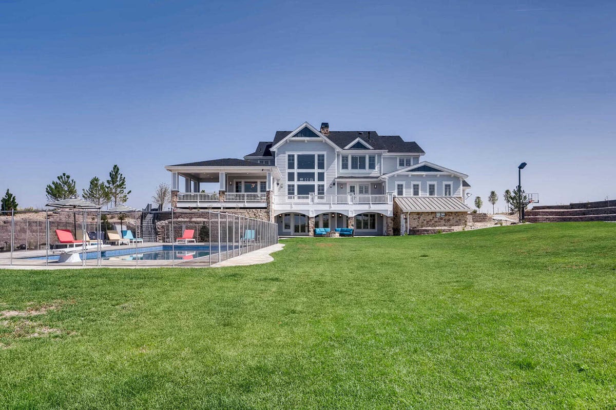 Long shot of the backyard of a large house with a private pool and an expansive lawn built by Sheffield Homes in Parker, CO
