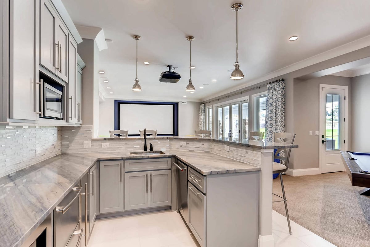 Lower-level premium wet bar with a marble countertop and gray cabinets in a custom home by Sheffield Homes in Parker, CO