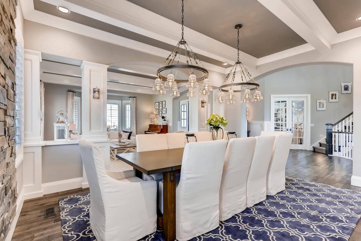 Modern dining room with a large dining table and a fancy pendant chandelier in a custom home by Sheffield Homes in Parker, CO