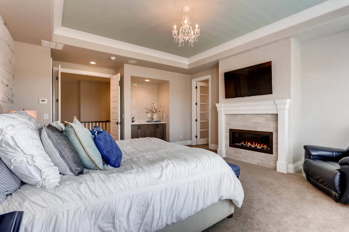 Premium master bedroom with elegant light fixtures, a mini wetbar, and a single sofa in a Sheffield Homes home in Parker, CO