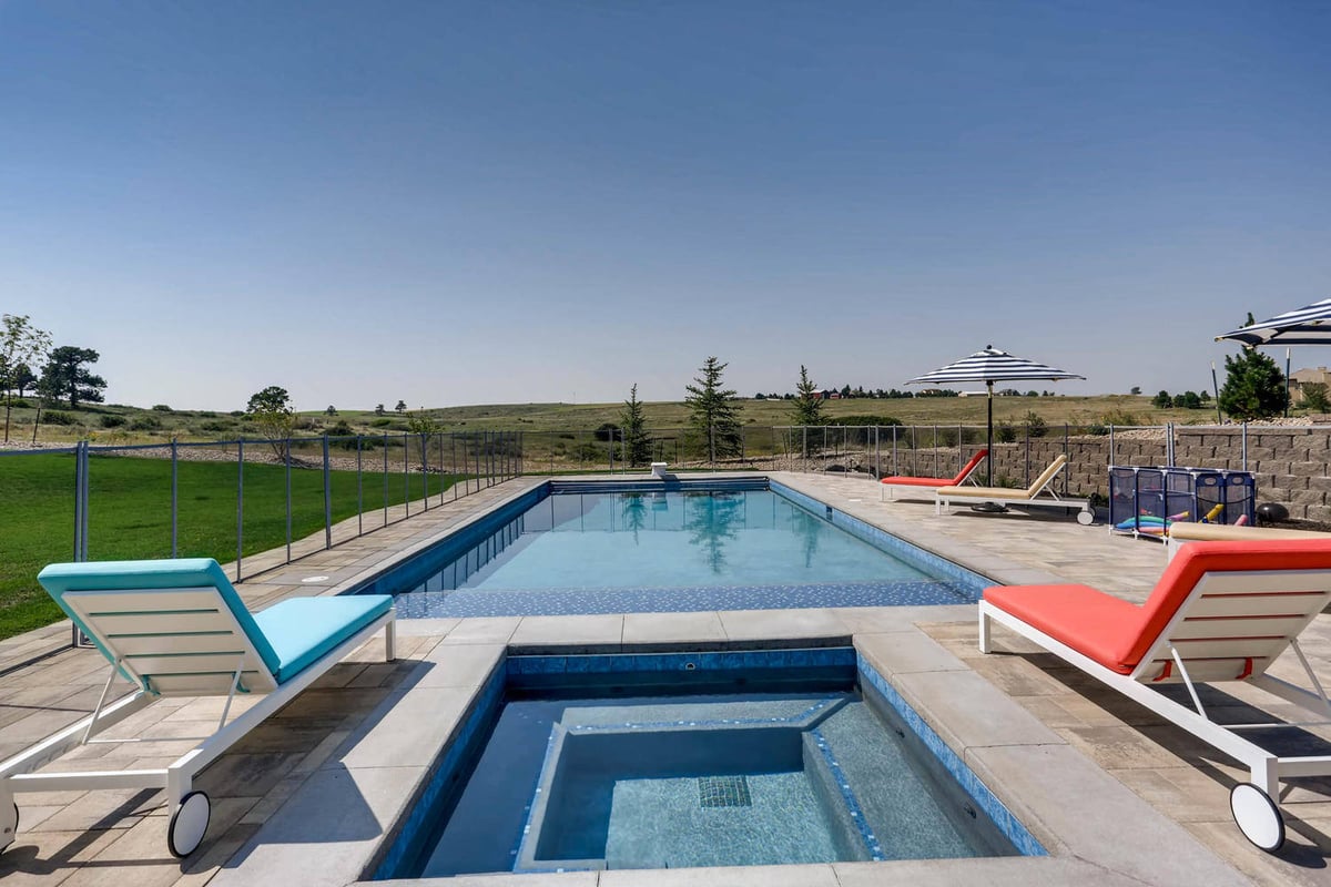 Private pool with fresh water, umbrella sheds, and pool loungers in a custom home lawn by Sheffield Homes in Parker, CO