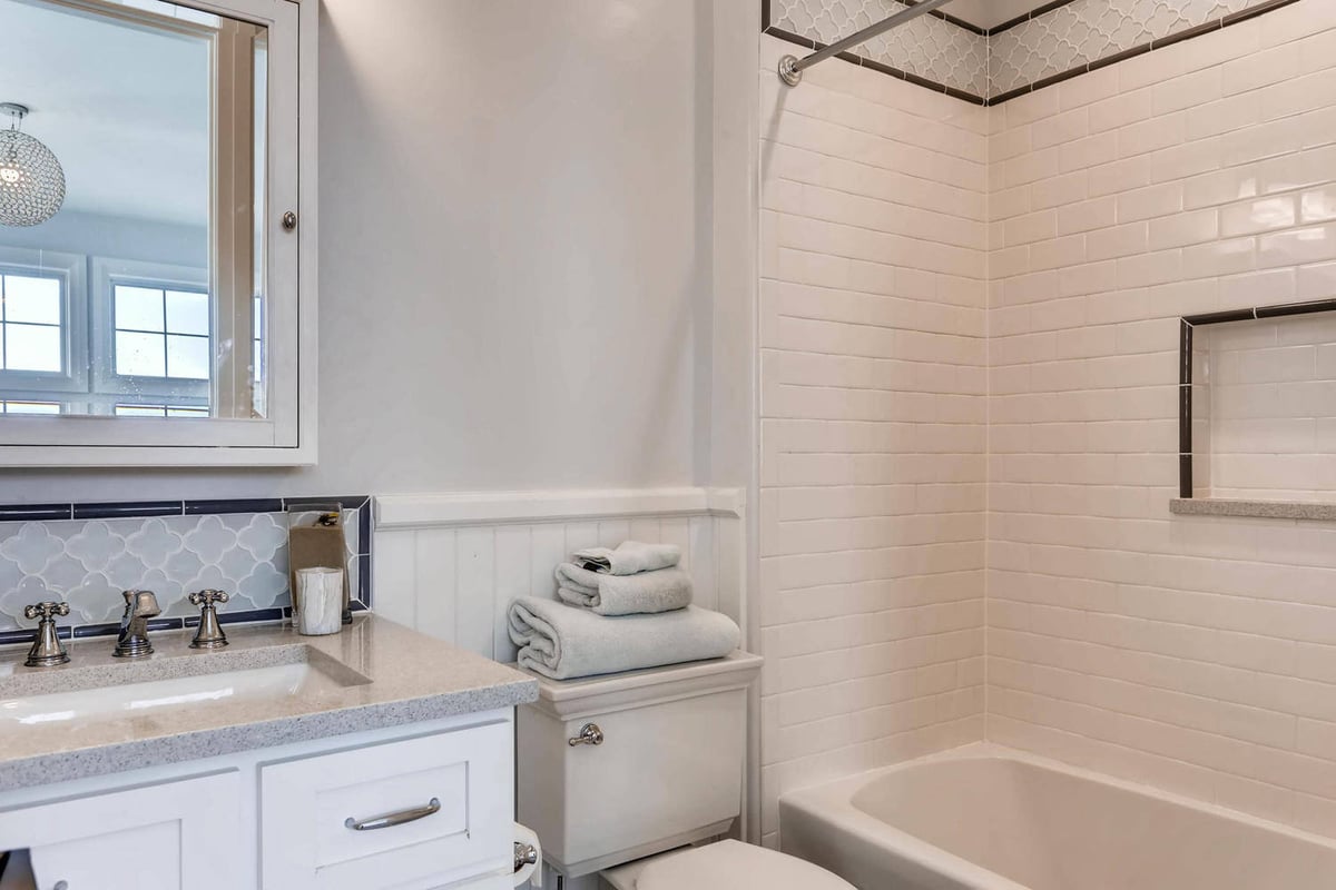 Second-floor bathroom with a single vanity, a toilet, and a shower-tub combo in a custom home by Sheffield Homes, Parker, CO