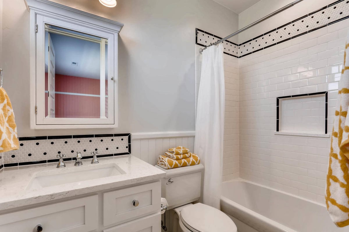 Second-floor bathroom with a wash basin, toilet, and shower area with a curtain in a Sheffield Homes home in Parker, CO
