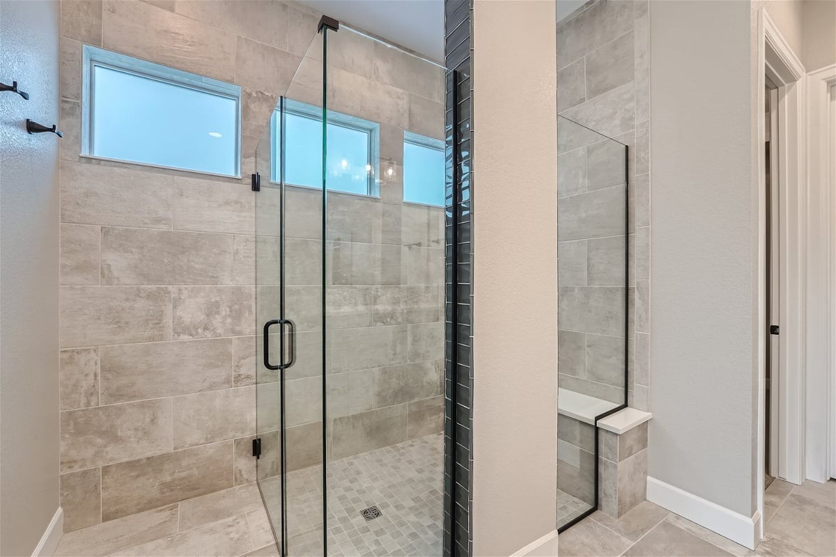 Bathroom with glass-enclosed shower area, wall tiling, and a couple of tiny windows in a Sheffield Homes home in Superior, CO