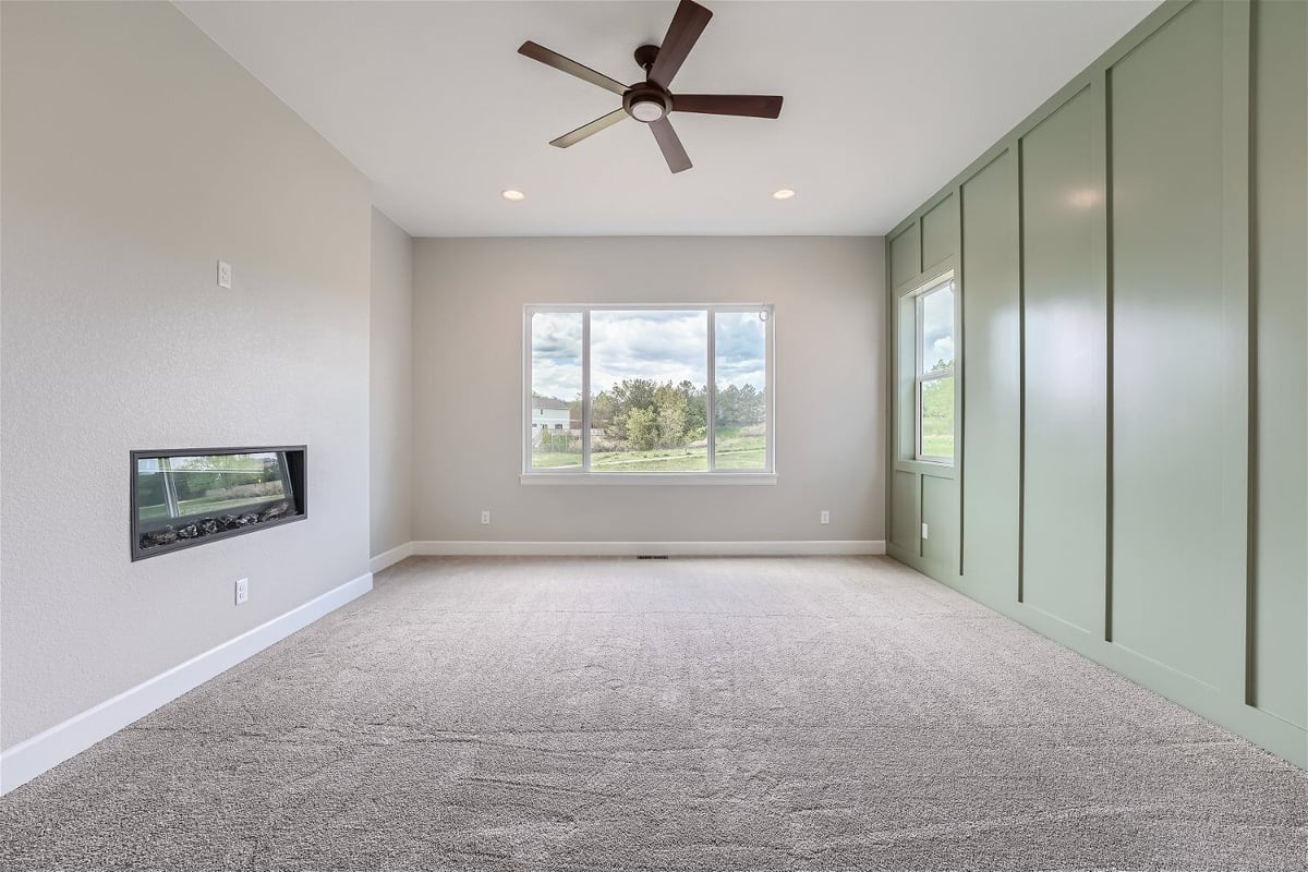 Bedroom with a green wall design, a mounted fireplace, and a front sliding window in a Sheffield Homes home in Superior, CO