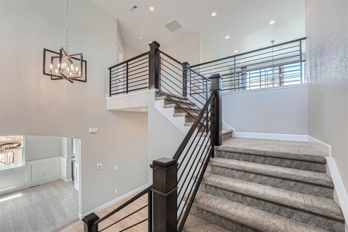 Detailed second-floor stairways with wooden railings and carpeted steps in a Sheffield Homes home in Superior, CO