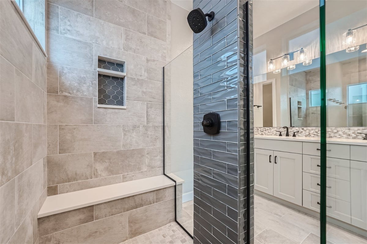 Inside the shower room of a modern bathroom, with dual vanities visible outside, in a Sheffield Homes home in Superior, CO