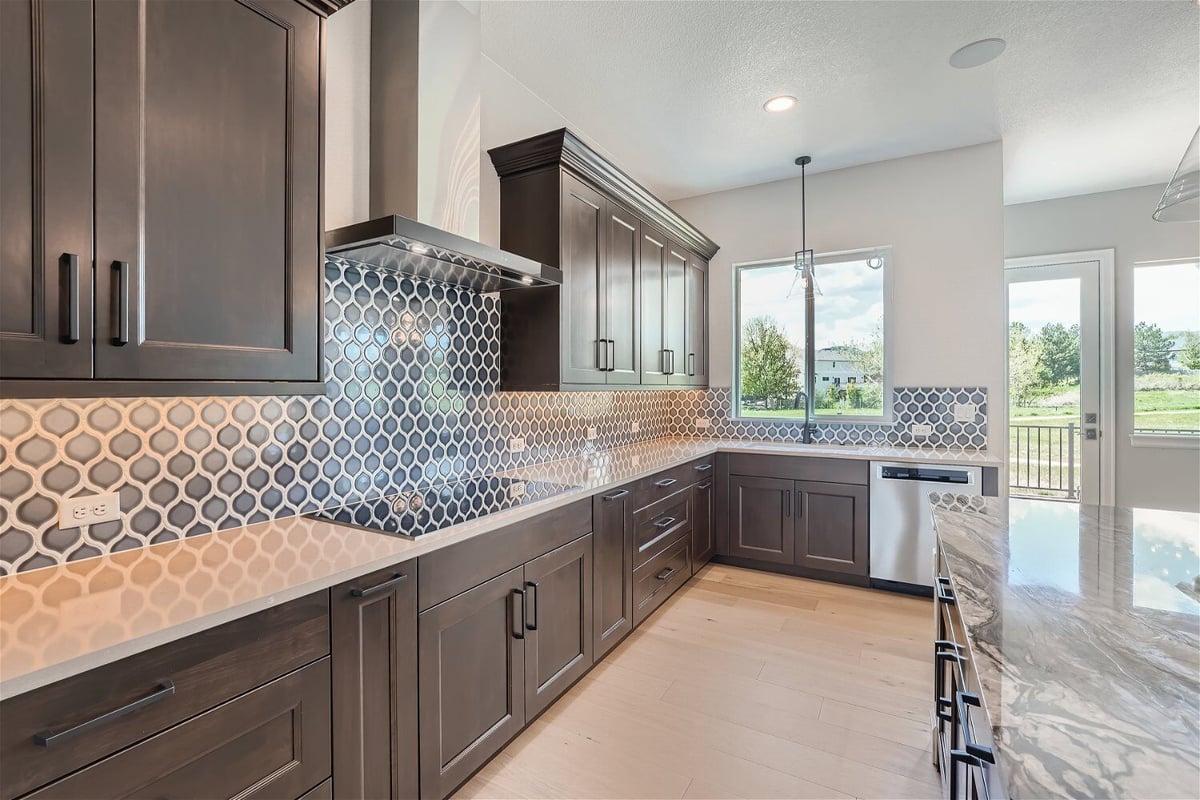 Kitchen island with a granite countertop and wooden cabinetry for storage in a custom home by Sheffield Homes in Superior, CO