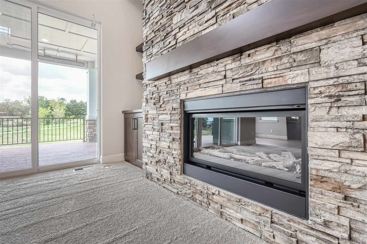 Living room close-up detail featuring a mounted fireplace in a stone accent wall in a Sheffield Homes home in Superior, CO