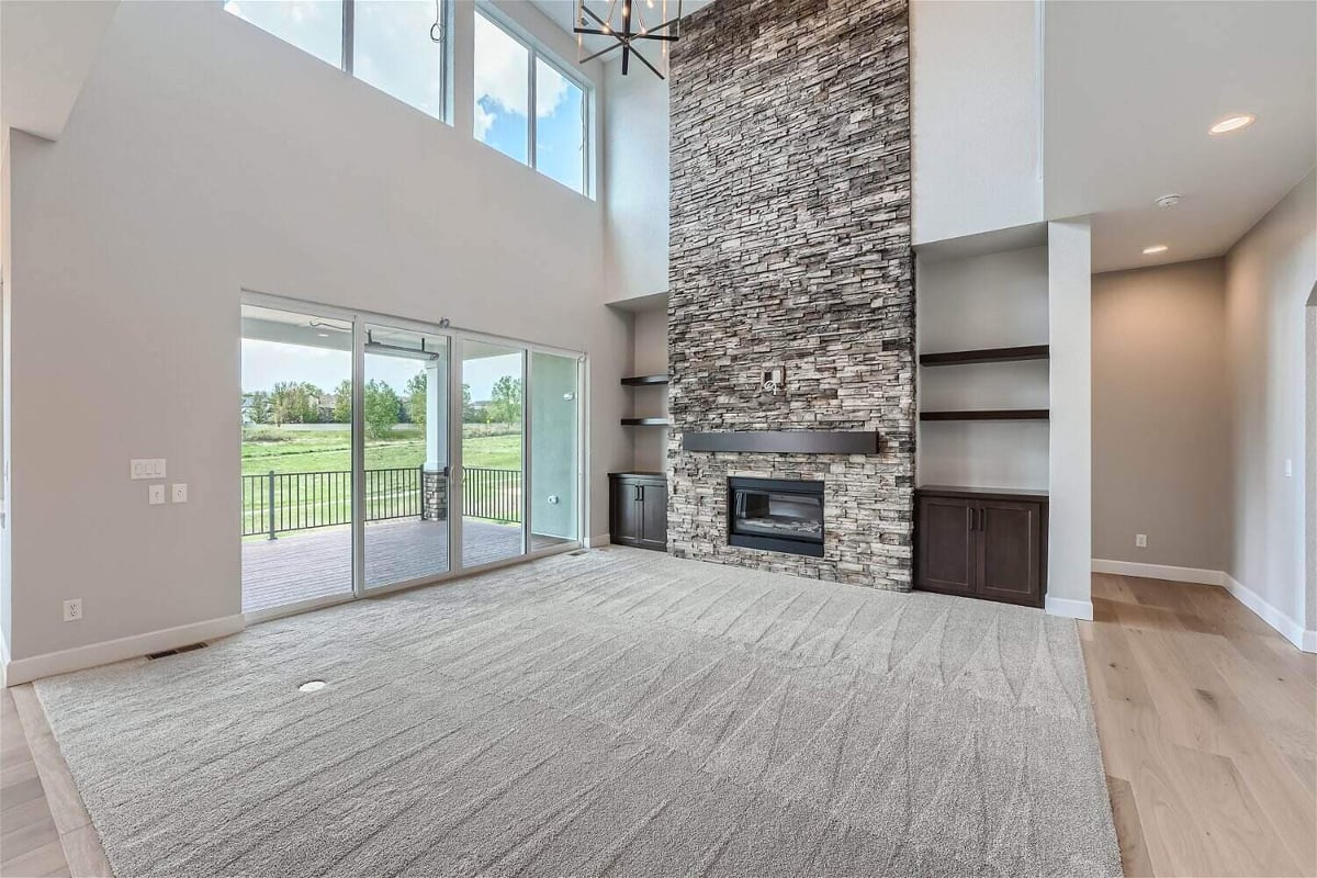 Living room with a fireplace, a floor carpet, and sliding doors leading to the patio in a Sheffield Homes home, Superior, CO