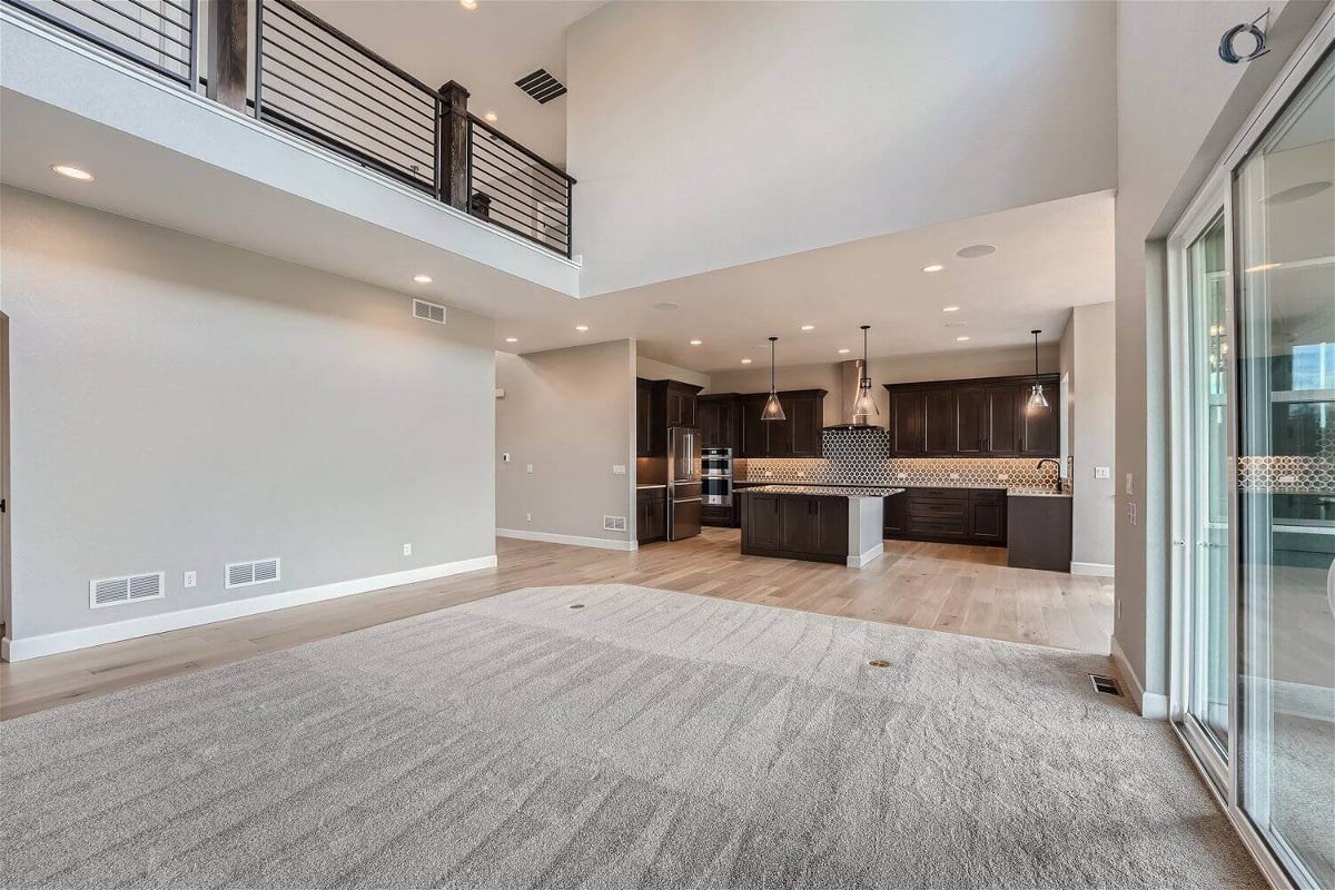 Living room with a floor carpet and a modern open kitchen visible in the corner in a Sheffield Homes home in Superior, CO