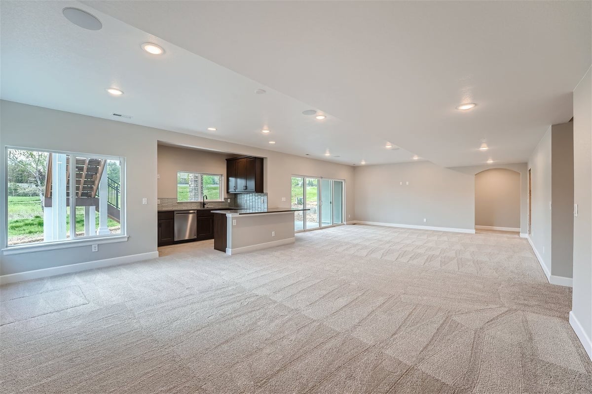 Lower-level family room with carpet flooring, a wetbar, and sliding windows in a Sheffield Homes home in Superior, CO