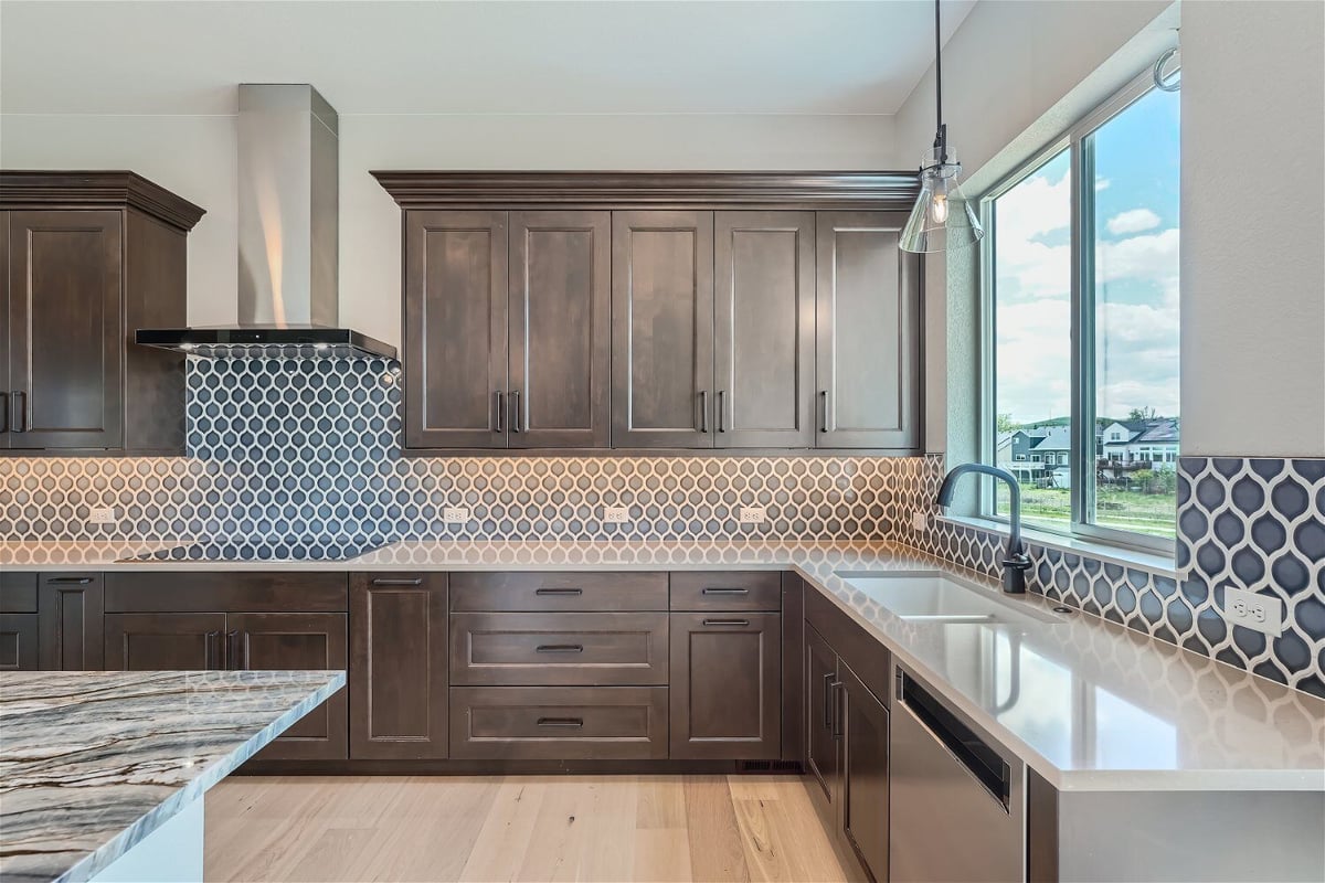 Open kitchen with light fixtures, wooden cabinetry, and a sliding window in a custom home by Sheffield Homes in Superior, CO