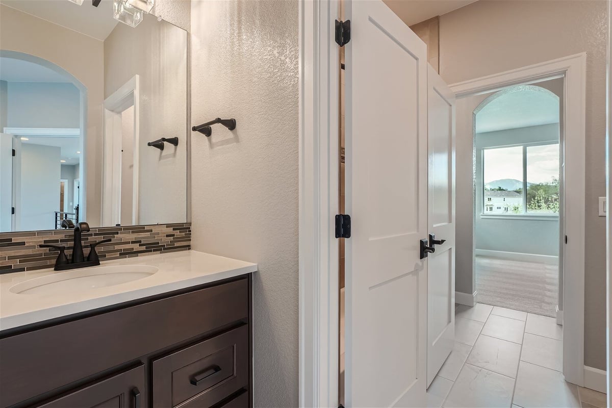 Second-floor Jack and Jill bathroom with a wash basin faucet and an open door in a Sheffield Homes home in Superior, CO