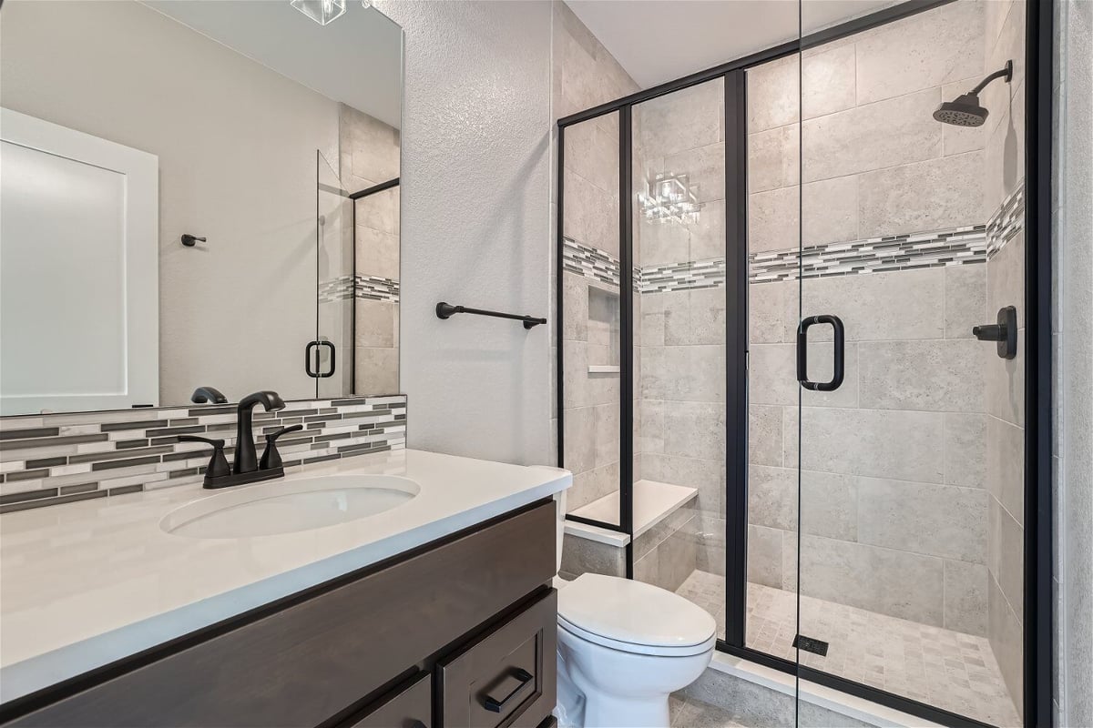 Second-floor bathroom with a modern vanity, toilet seat, and shower room in a Sheffield Homes home in Superior, CO
