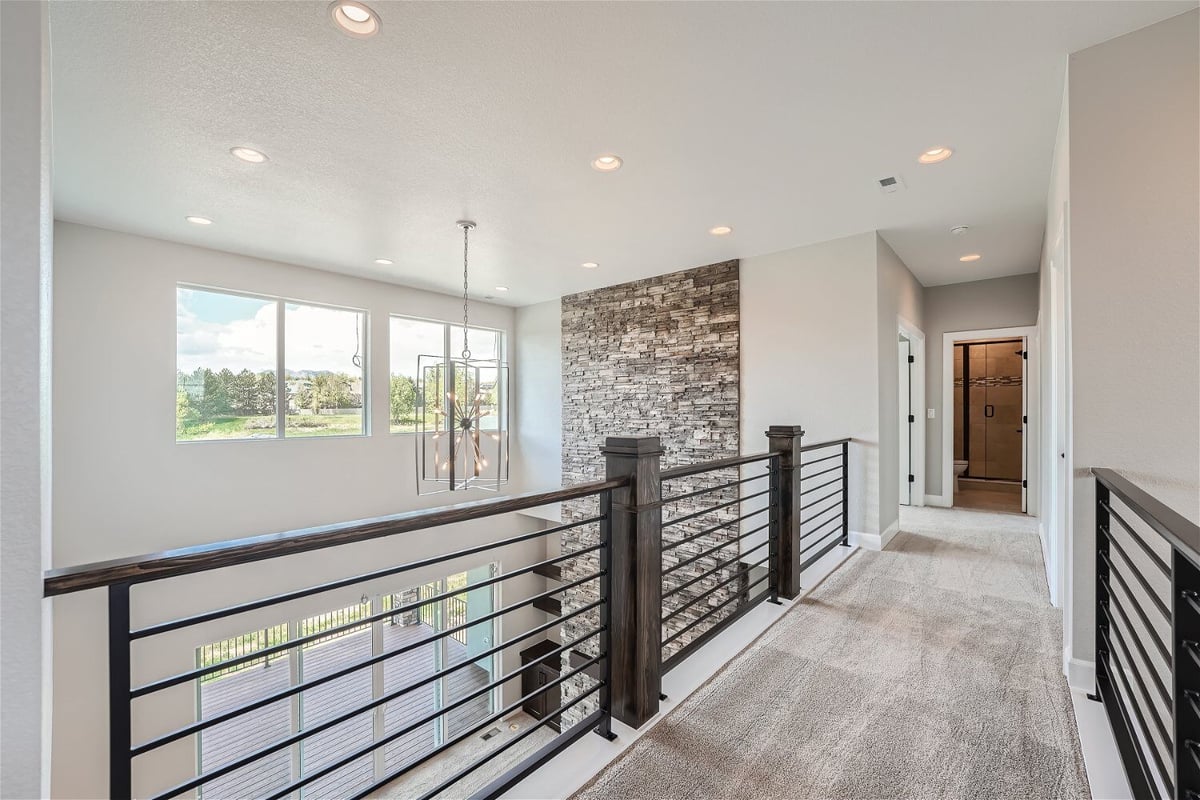 Second-floor landing with a wooden stairway fence and carpet flooring in a Sheffield Homes home in Superior, CO