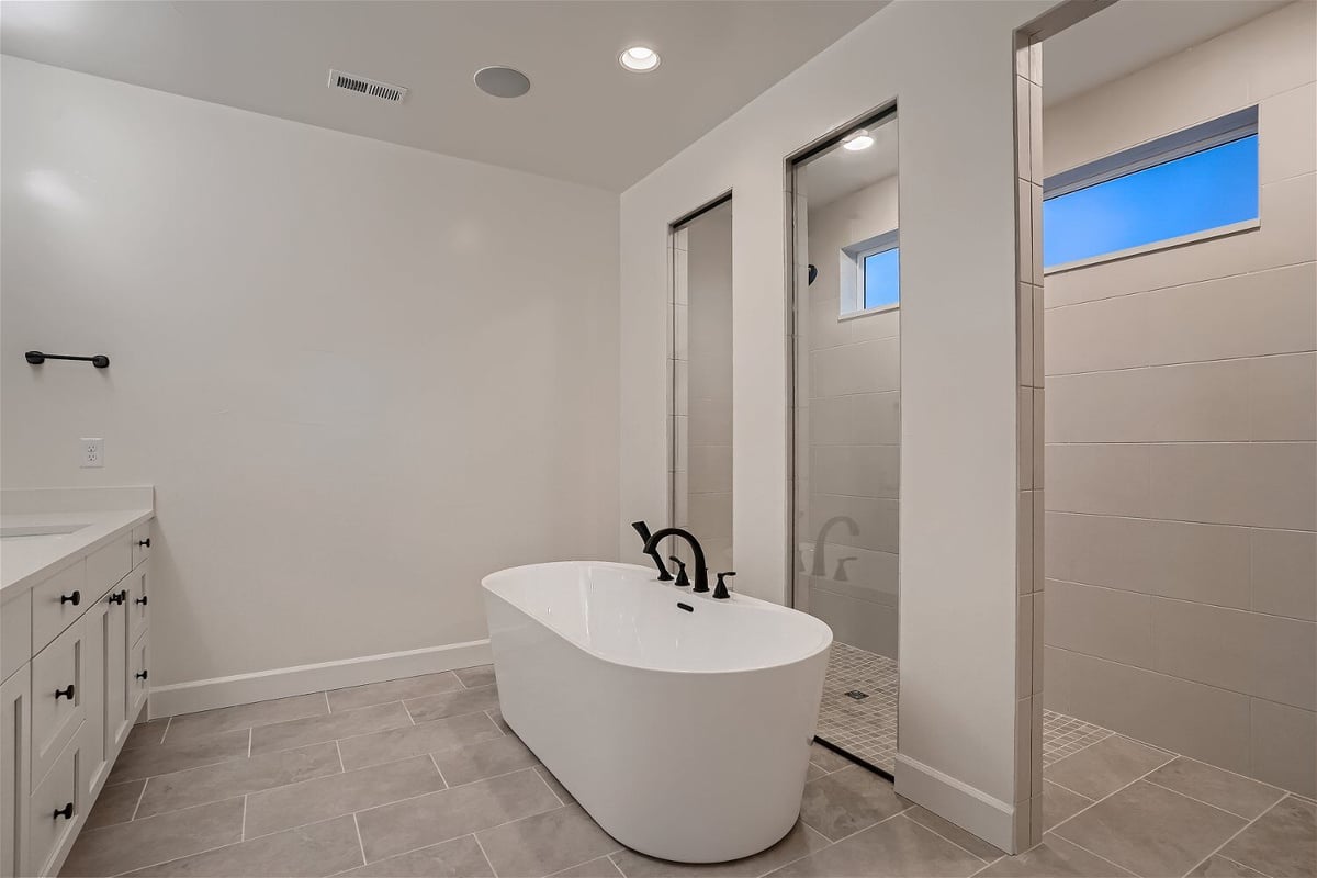 Bathroom with a free-standing bathtub and a shower enclosed with marble tiling in a Sheffield Homes home in Superior, CO