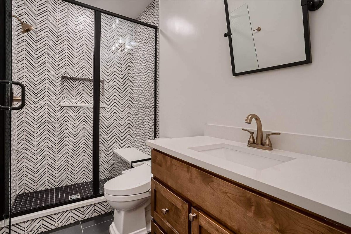 Bathroom with a vanity, toilet, and shower room featuring custom-tiled walls in a Sheffield Homes home in Superior, CO