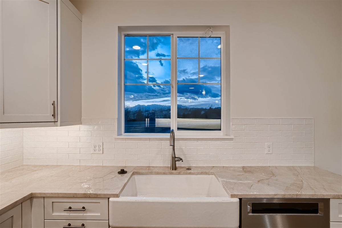 Closeup kitchen sink and faucet with marble countertop and a sliding window behind, in a Sheffield Homes home in Superior, CO