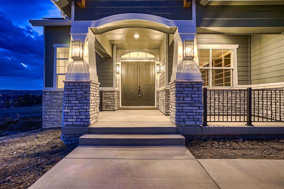Exterior front entrance of a custom home with stone accent design and a wooden main door by Sheffield Homes in Superior, CO