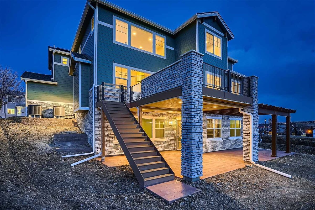 Exterior rear view of a custom home with a patio and deck featuring a stone accent design by Sheffield Homes in Superior, CO