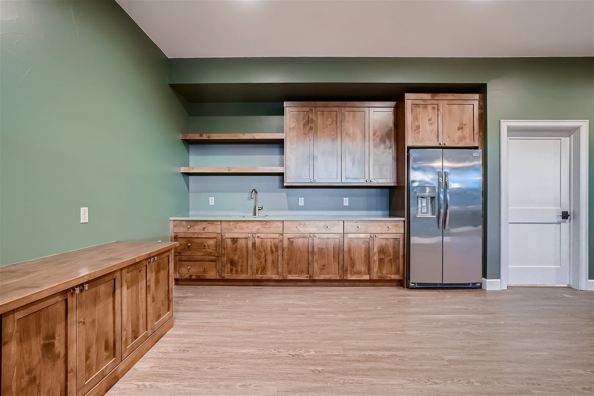 Family room with a wet bar and a side dresser made of natural wood inside a custom home by Sheffield Homes in Superior, CO