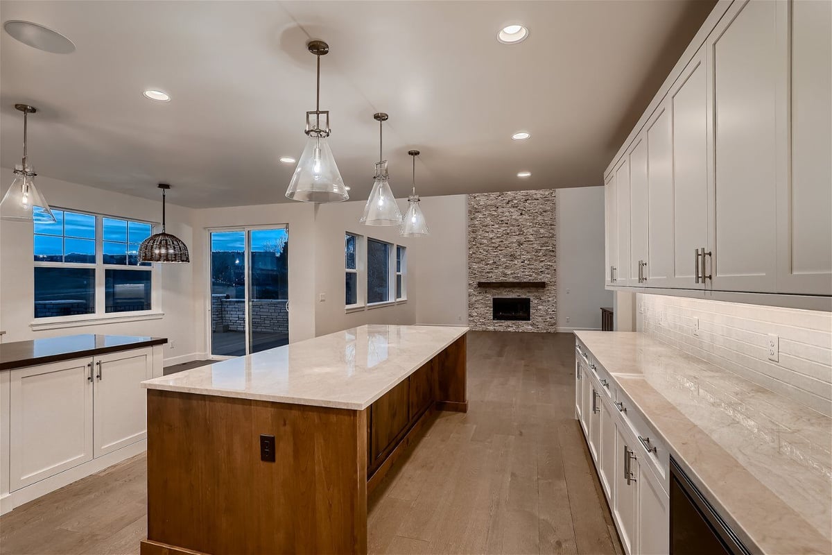Kitchen with a central island, sleek white cabinetry, and elegant light fixtures in a Sheffield Homes home in Superior, CO