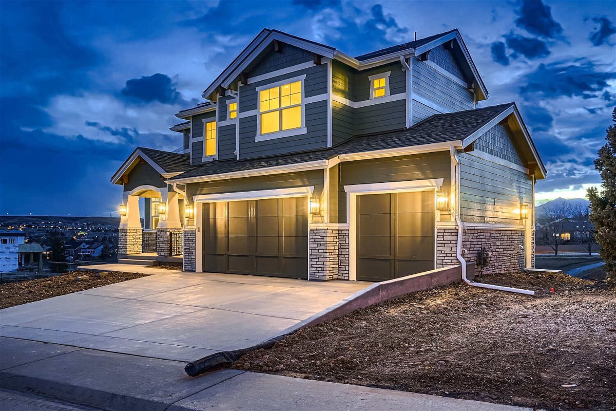 Low-light exterior front view of a home with elegant light fixtures and a paved pathway by Sheffield Homes, Superior, CO