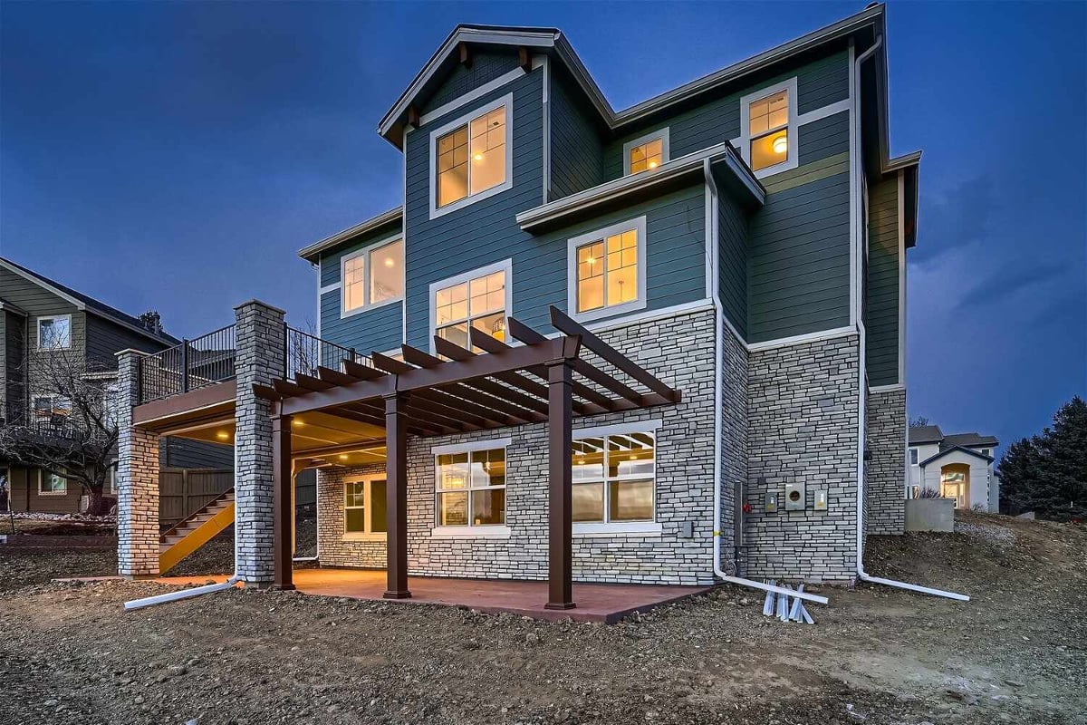 Low-light exterior rear view of a custom home with stone accent walls design by Sheffield Homes in Superior, CO