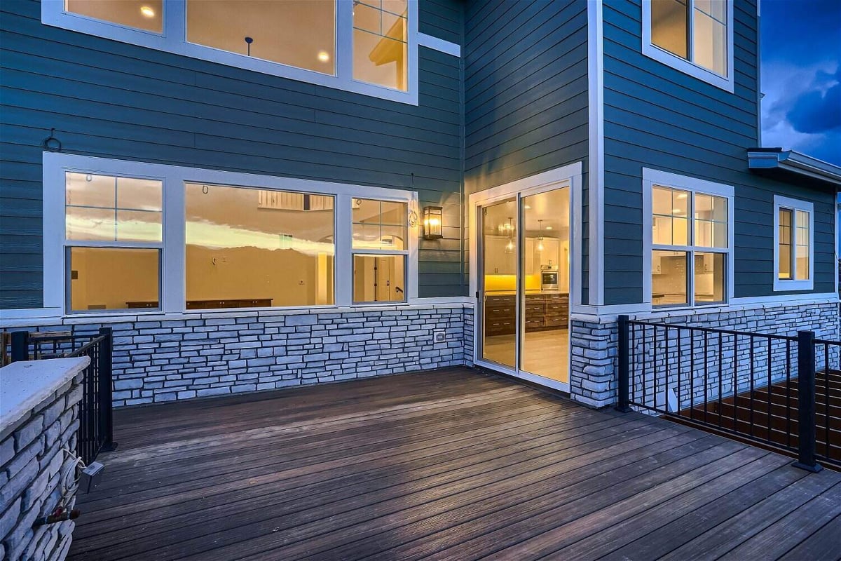 Low-light view of a custom deck with a black metal fence and stone accent columns in a Sheffield Homes home in Superior, CO
