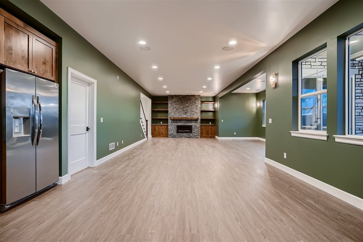 Lower-level family room with forest green walls, steel appliances, and a fireplace in a Sheffield Homes home in Superior, CO