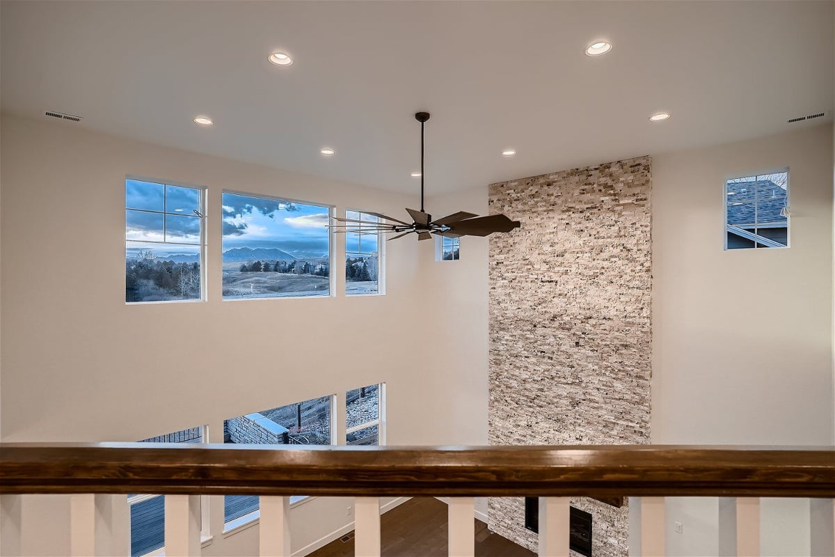 Main ground hall view from the upper stair railing with a ceiling fan in a Sheffield Homes home in Superior, CO