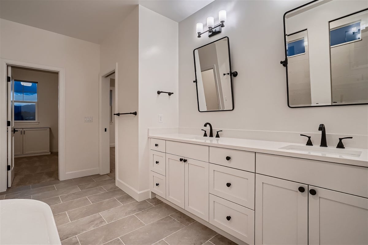 Primary bathroom with dual vanities, white cabinets, and elegant light fixtures in a Sheffield Homes home in Superior, CO