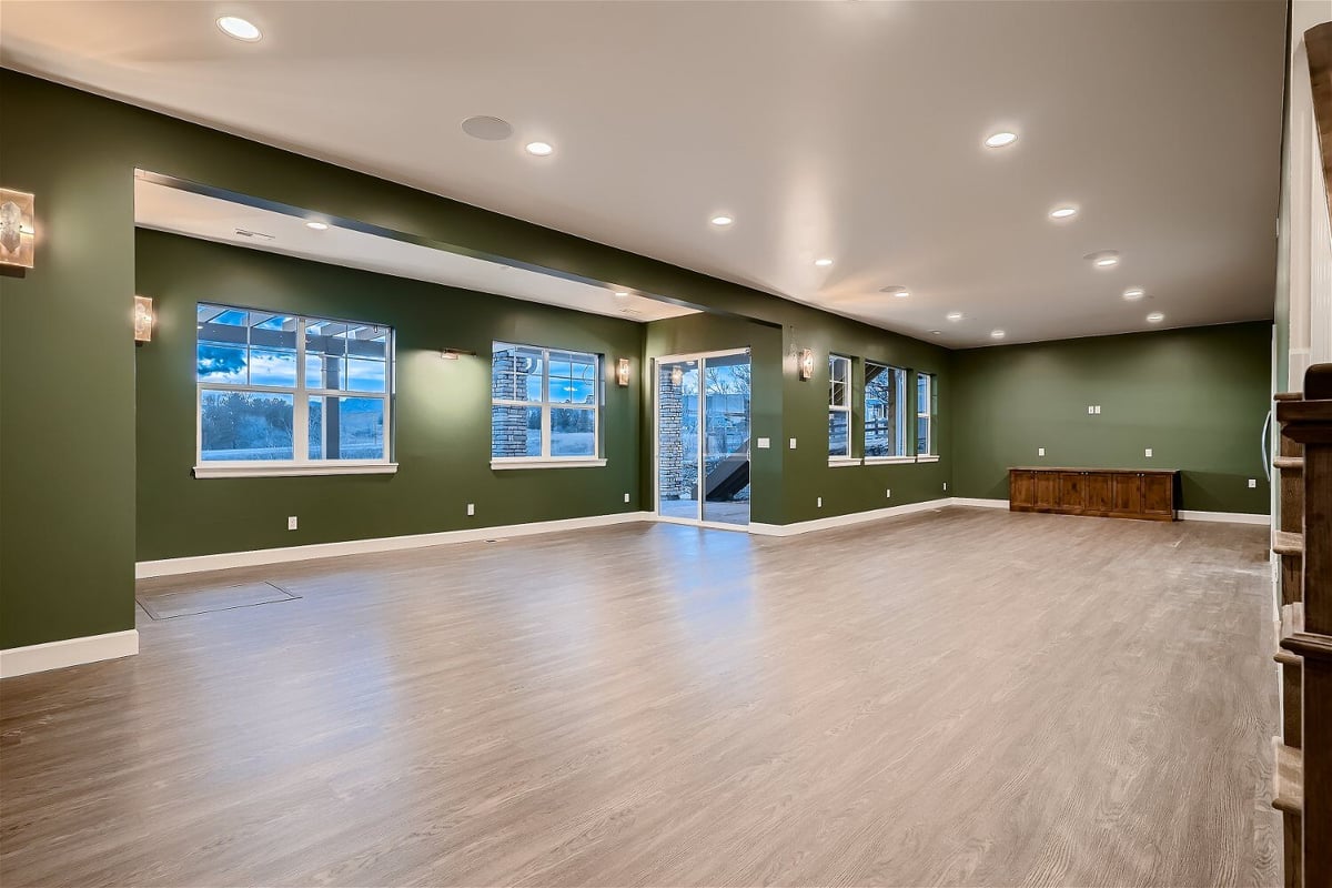 Spacious lower-level family room with forest green walls, sliding windows, and doors in a Sheffield Homes home, Superior, CO