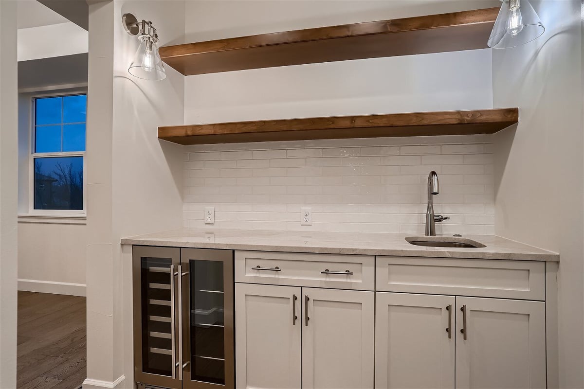Wetbar details featuring a sink with a marble countertop and wooden cabinetry in a Sheffield Homes home in Superior, CO