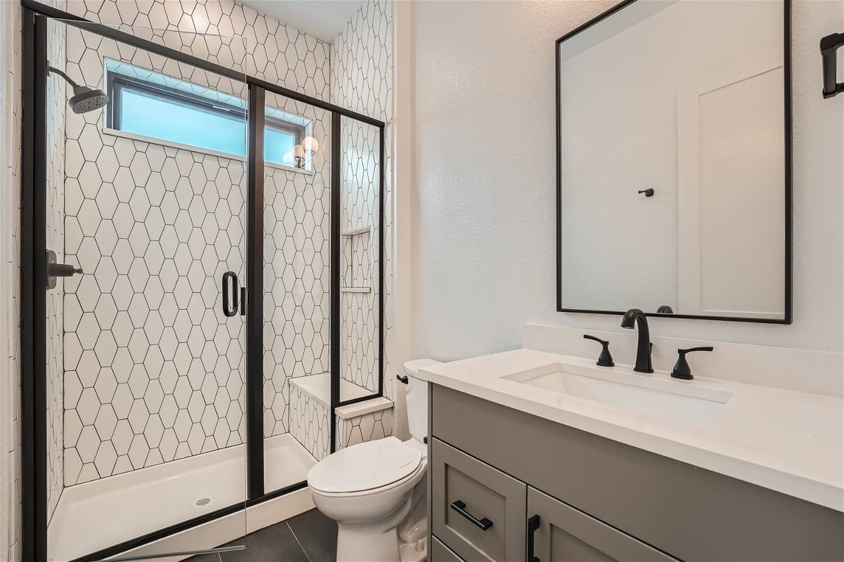 Bathroom with a single vanity, a toilet, and a modern glass-enclosed shower room in a Sheffield Homes home in Superior, CO
