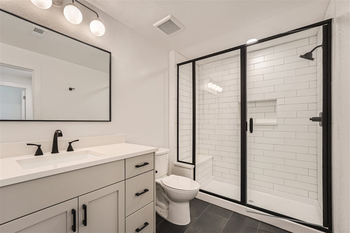 Bathroom with a vanity, toilet, and a glass-enclosed shower room with white tiles in a Sheffield Homes home in Superior, CO