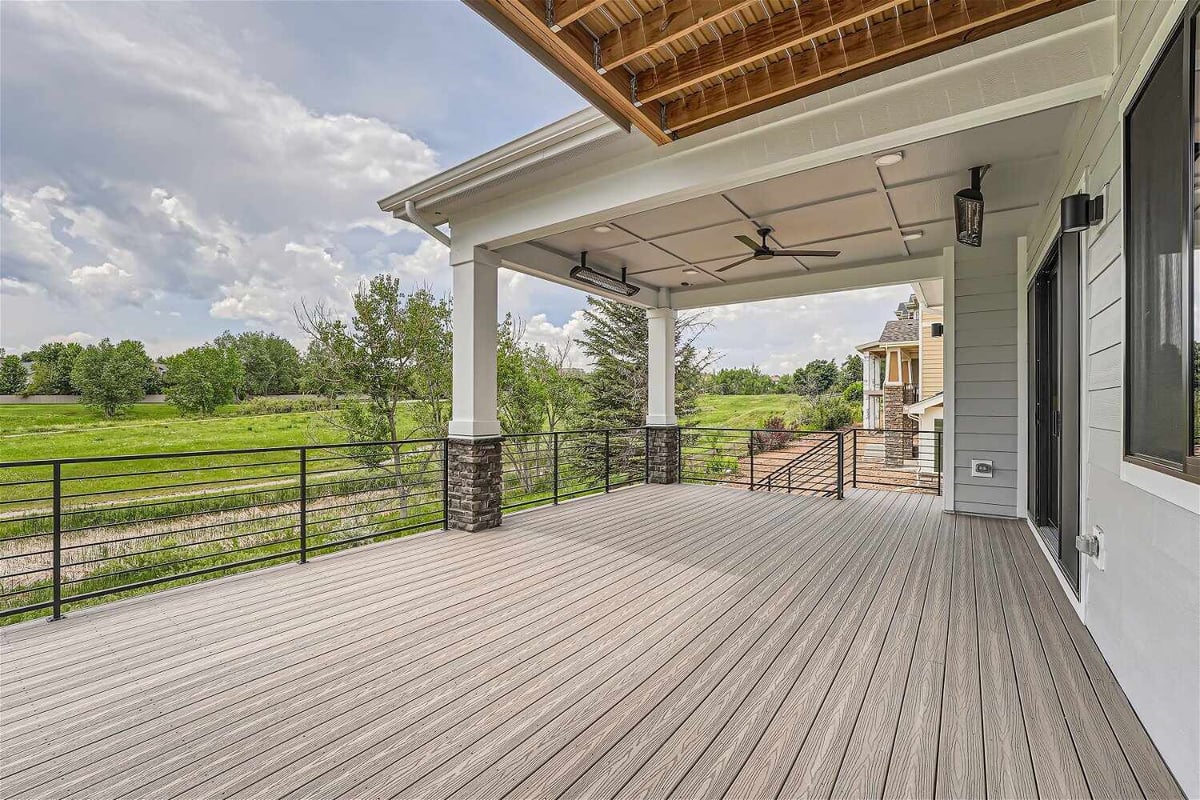 Deck with a metal fence and a wooden hood, offering elevated views of greenery from a Sheffield Homes home in Superior, CO