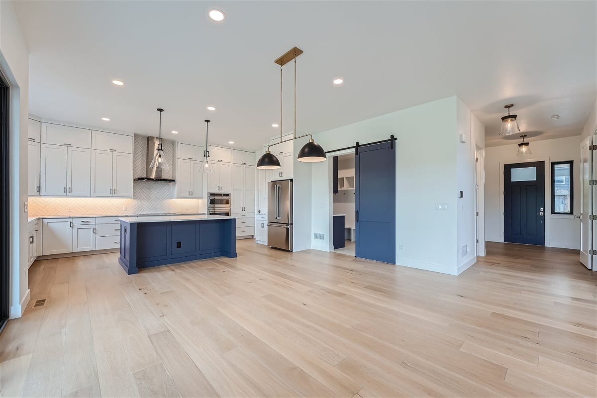 Dining room with wood texture flooring and a modern open kitchen in a custom home by Sheffield Homes in Superior, CO