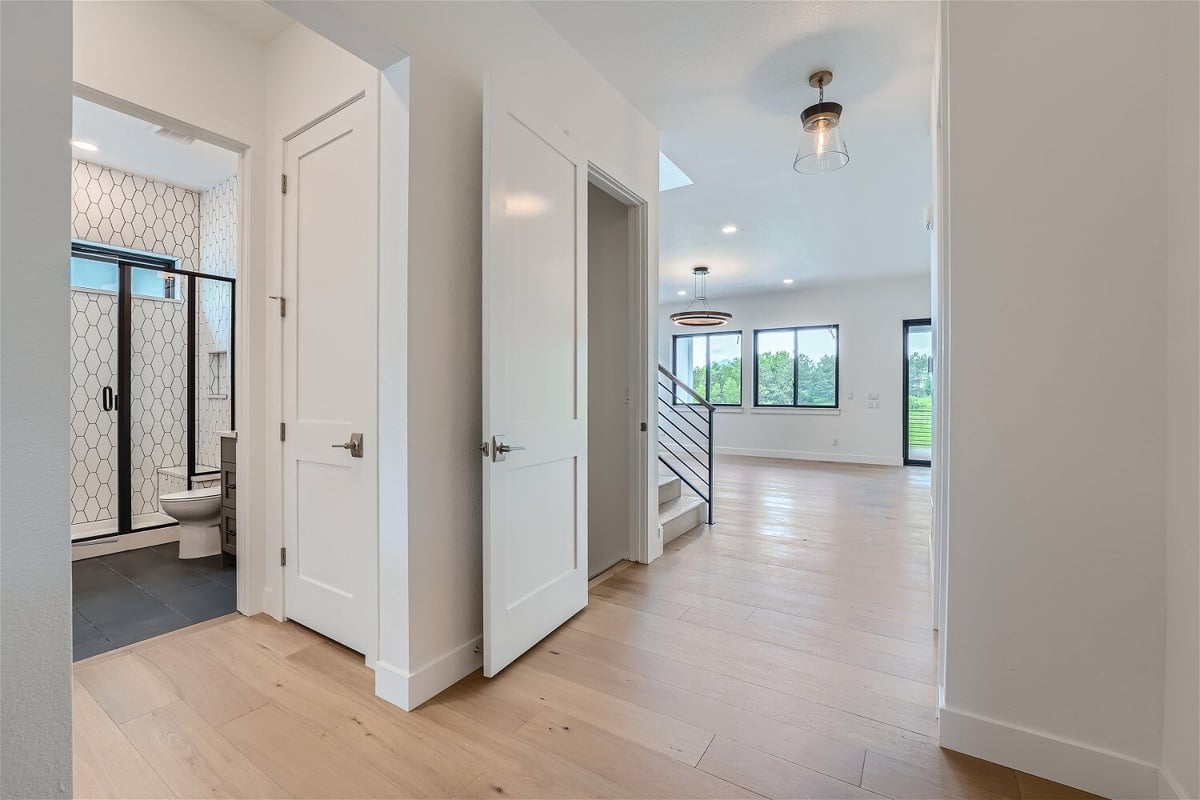 Foyer inside a custom home with a view of the bathroom and living room by Sheffield Homes in Superior, CO