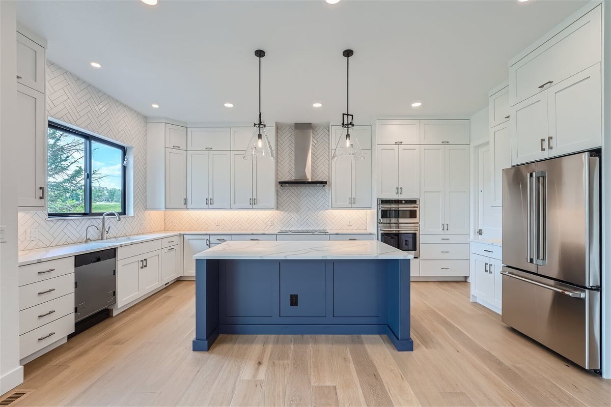 Kitchen with a central counter featuring blue and white cabinets and steel appliances in a Sheffield Homes home, Superior, CO