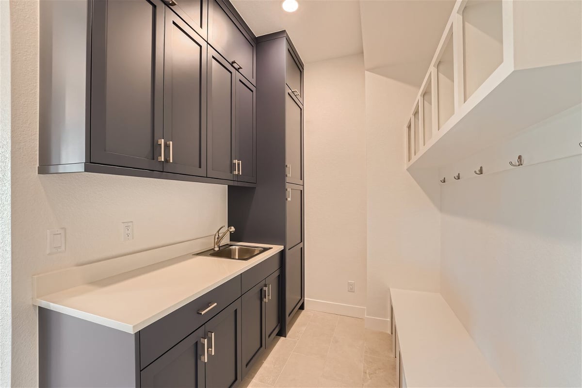 Laundry room with a sink counter, dark grey cabinets, and additional storage slots in a Sheffield Homes home in Superior, CO