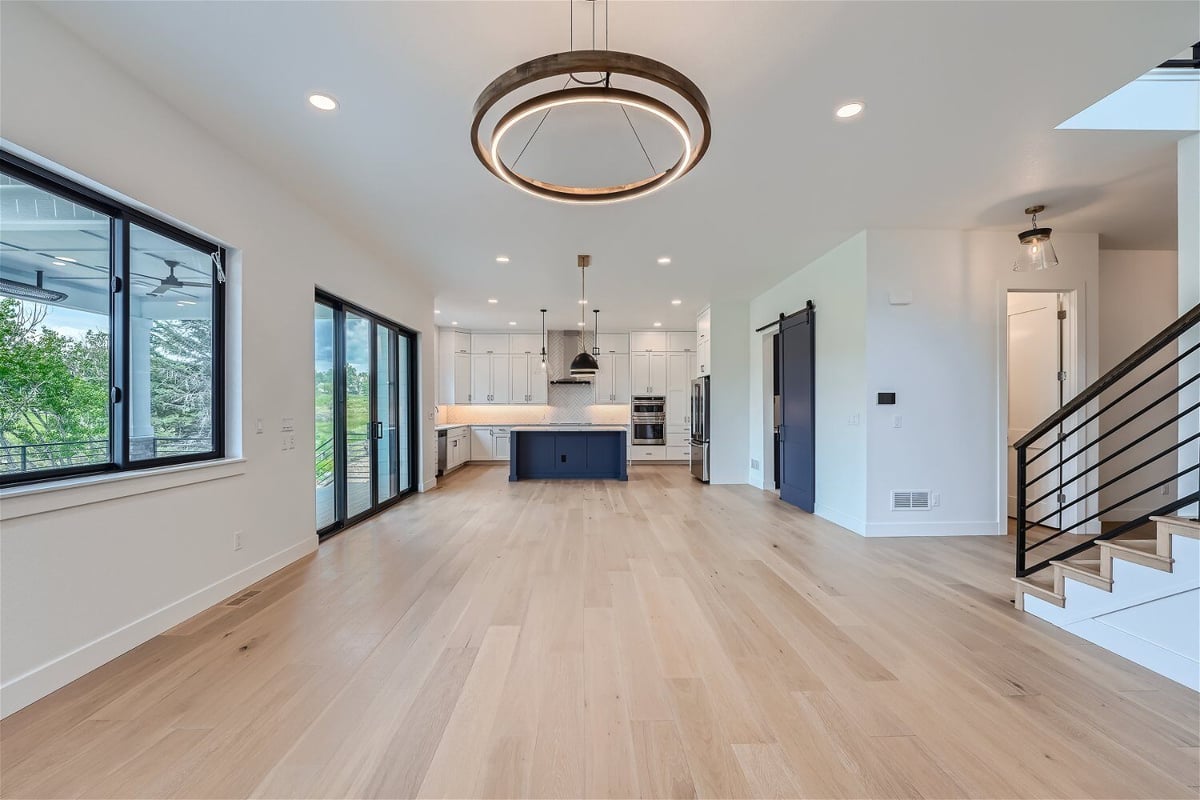 Living room with a chandelier, windows, and an open kitchen visible in the corner of a Sheffield Homes home in Superior, CO