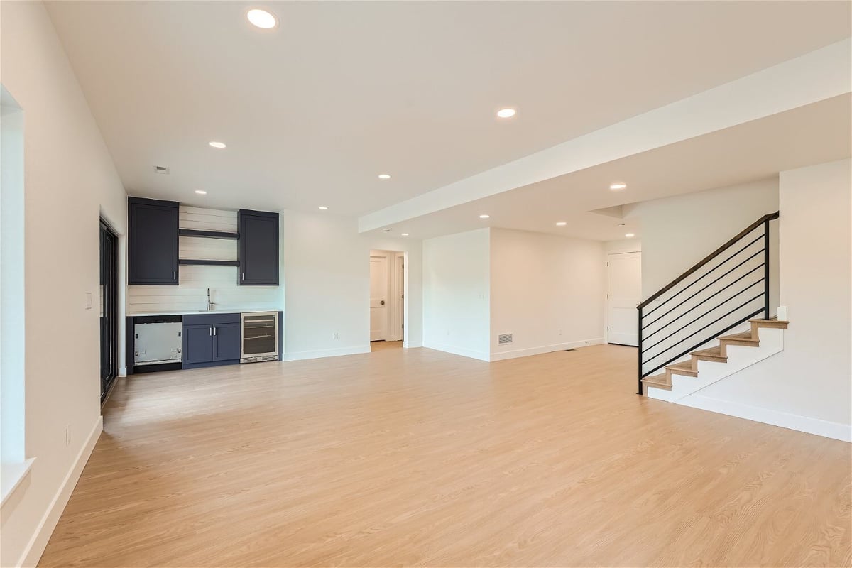 Lower-level family room with a staircase and a corner wetbar next to the main door in a Sheffield Homes home in Superior, CO
