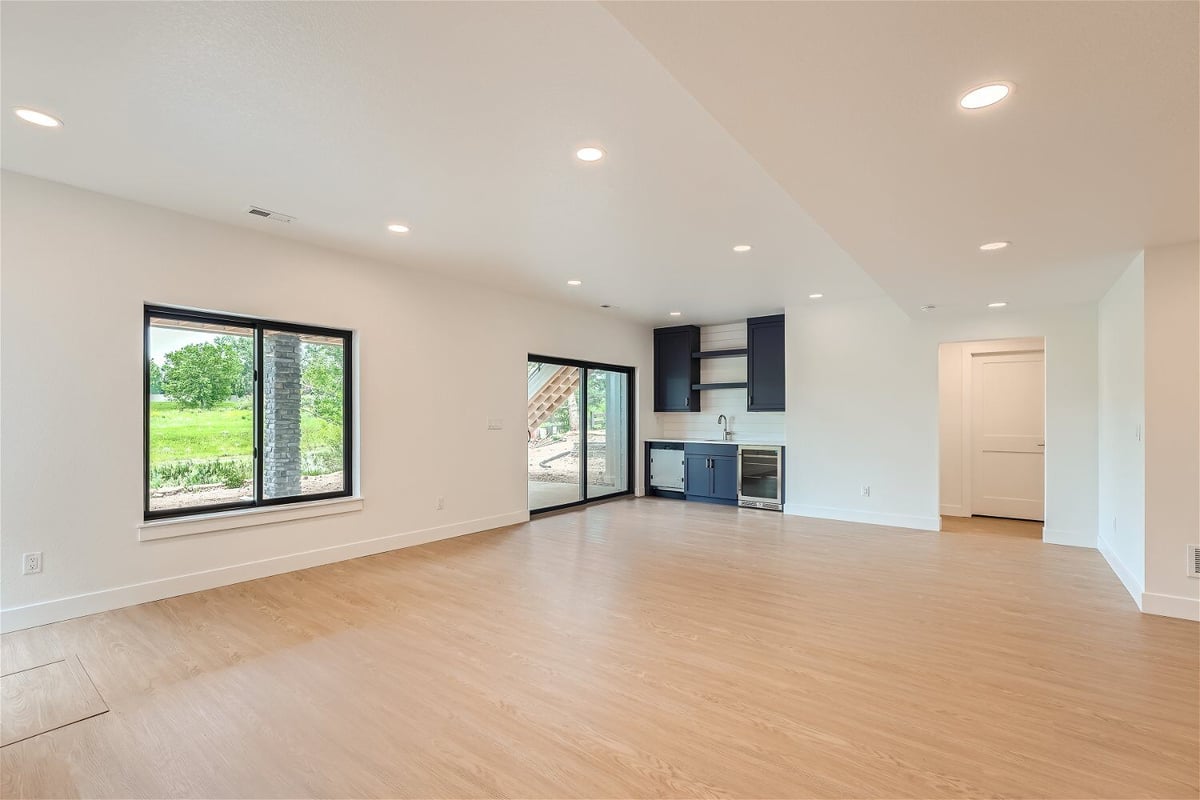 Lower-level family room with wood texture flooring and a corner wetbar with the door in a Sheffield Homes home, Superior, CO