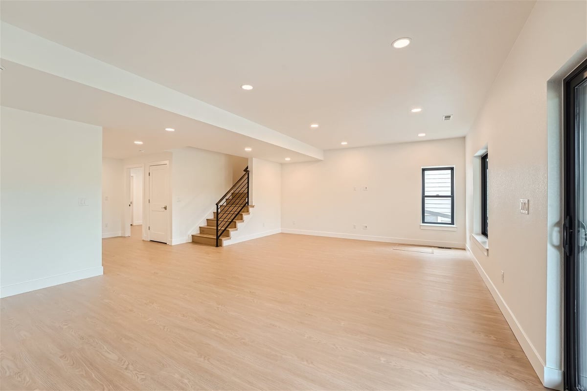 Lower-level family room with wood texture flooring, a couple of windows, and doors in a Sheffield Homes home in Superior, CO