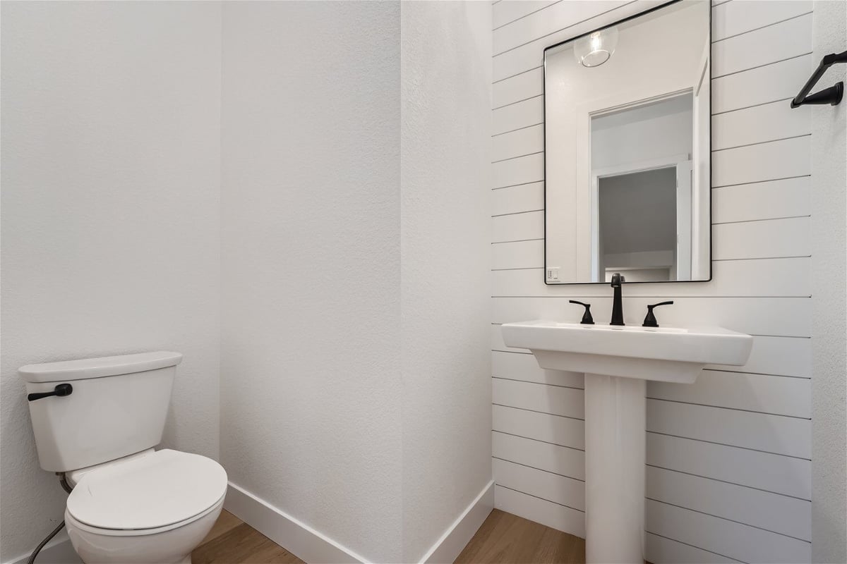 Powder room with a single wash basin, a mirror, and a toilet seat in a custom home by Sheffield Homes in Superior, CO