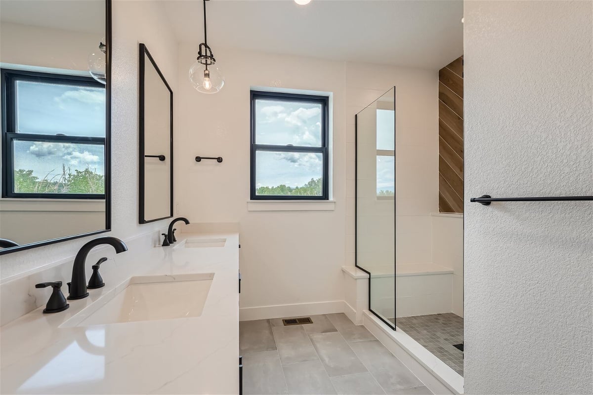 Second-floor bathroom with dual vanities, a shower enclosure, and elegant lighting in a Sheffield Homes home in Superior, CO